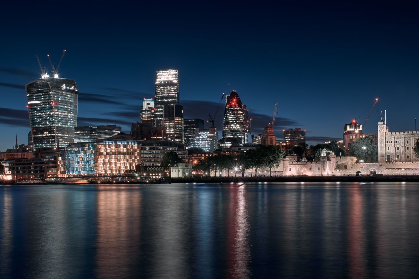 City of London skyline and the Tower of London reflected in the Thames at night