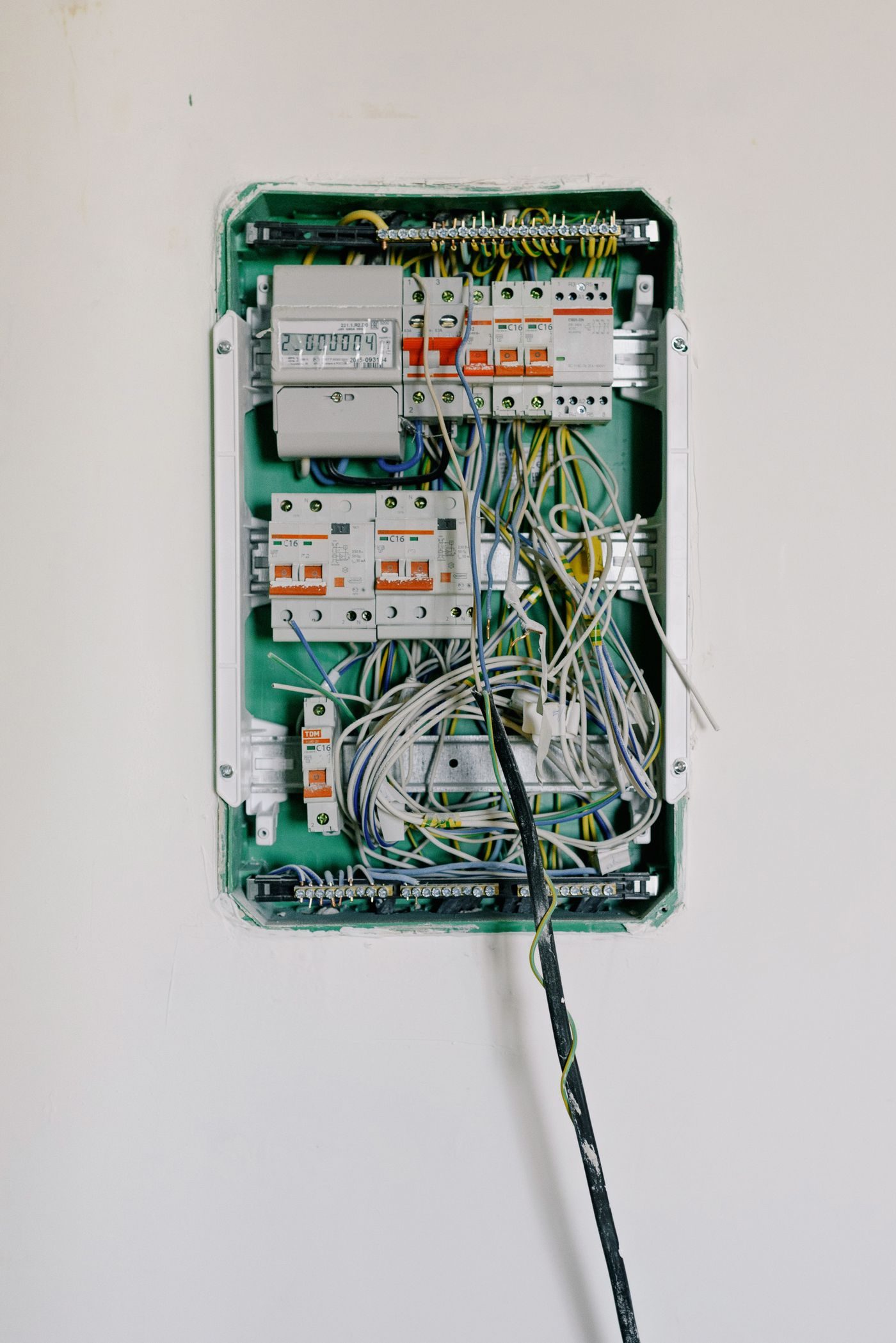 Open consumer unit on a white wall with circuit breakers and new wiring during an upgrade