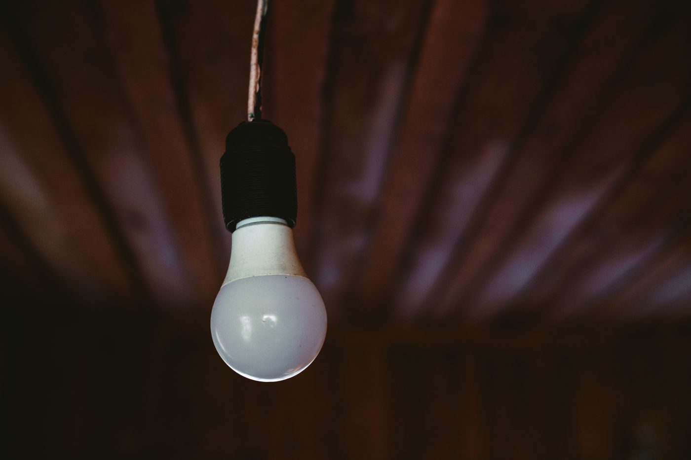 Single bare light bulb hanging from a dark ceiling